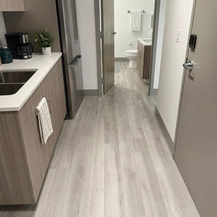 LVT flooring installed throughout an apartment unit kitchen and bathroom without transitions